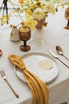 a white table with yellow napkins and silverware