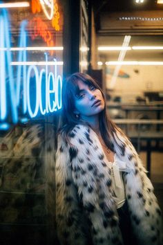 a woman standing in front of a neon sign