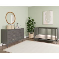 a baby's room with a crib, dresser and mirror