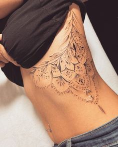 a woman's lower back tattoo with intricate designs on her stomach and the bottom part of her body