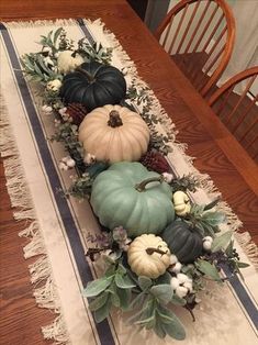 a table runner with pumpkins and greenery on it