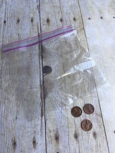 some coins are laying on the floor next to a plastic bag with a purple stripe