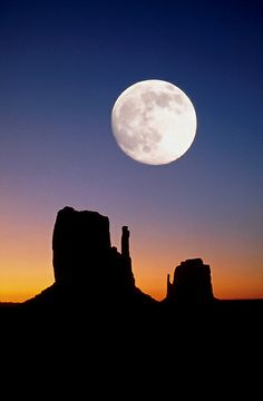 the moon is setting over monument rock formations