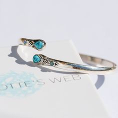 The Shakti Bangle is a stunning silver wrap-around cuff with genuine turquoise gemstones, opal cabochons, and traditional Rajasthani artwork in the classic ball design. With its summer-inspired gems, this enchanting piece of jewellery will lend a splash of colour to beachwear, boho dresses, and tailored office edits. In Hindu mythology, Shakti is a divine cosmic force, a feminine energy often used in meditation to manifest peace, love, health and success.  Wear the Shakti Turquoise Cuff solo or Bohemian Turquoise Bracelet With Gemstone Accents, Bohemian Turquoise Bracelets With Gemstone Accents, Adjustable Turquoise Bracelet With Gemstone Accents, Manifest Peace, Charlotte's Web, Gemstone Bangle, Ball Design, Stacked Bangles, Turquoise Cuff