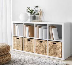 a white shelf with wicker baskets and books