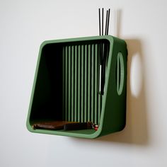 a green object with sticks sticking out of it's side hanging on a wall