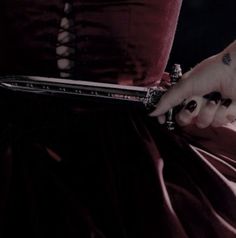 a woman in a red dress is holding a knife with her hand on the skirt