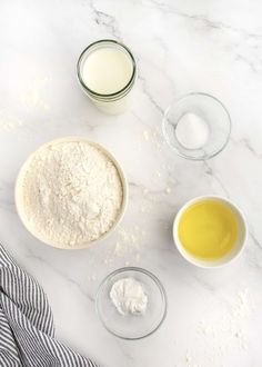 the ingredients to make this recipe are laid out on a white marble counter top, including flour, eggs and butter