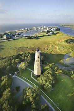 an aerial view of a lighthouse in the middle of a grassy area next to water