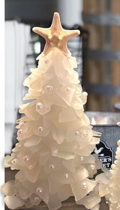 a white christmas tree with pearls and a starfish decoration on it's top