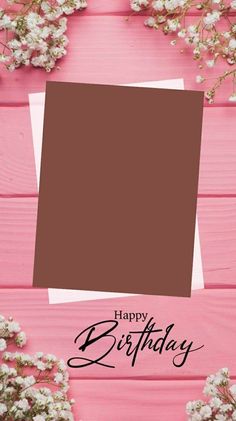 a pink wooden table with flowers and a brown square birthday card on top of it