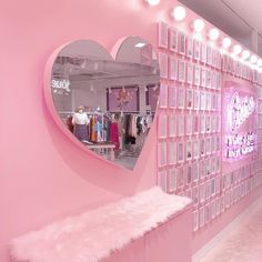 a heart shaped mirror hanging on the side of a pink wall next to a bench