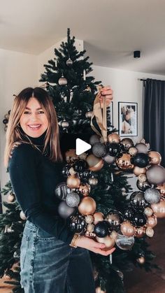 a woman standing in front of a christmas tree