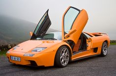 an orange sports car with its doors open