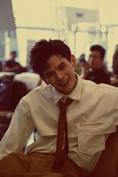 a man sitting in an airport wearing a shirt and tie