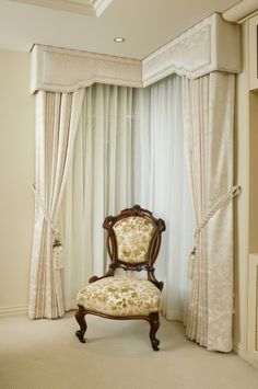 a chair sitting in the middle of a room with curtains on either side of it