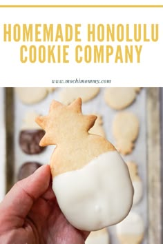 a hand holding a cookie in front of some cookies on a baking sheet with the words homemade honolu cookie company