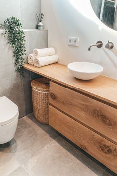 a white toilet sitting next to a wooden counter top in a bathroom under a mirror