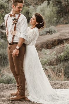 a bride and groom standing together in the woods