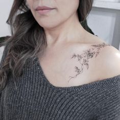 a woman with a flower tattoo on her left shoulder and right arm is looking at the camera