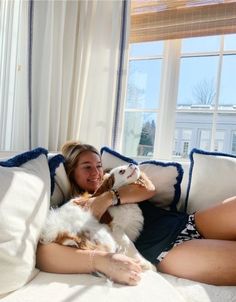 a woman laying on top of a couch holding a dog