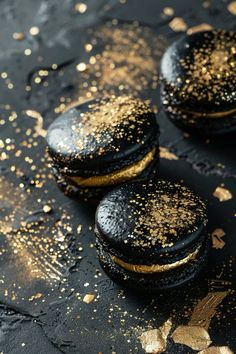 three black macaroons covered in gold flecks