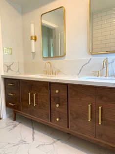 a bathroom with marble counter tops and two sinks in the same color as the cabinets