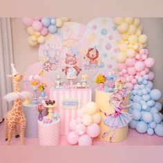 a pink and yellow birthday party with giraffes, balloons, cake and decorations