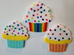 three cupcakes made out of perler beads on a white surface with multicolored dots