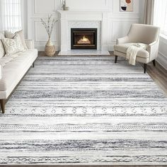 a living room with white furniture and a large rug on the floor in front of a fireplace