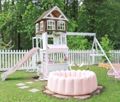 a pink play set in the yard with a slide and swing set next to it