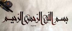 arabic calligraphy written in two languages on a sheet of paper next to some pens