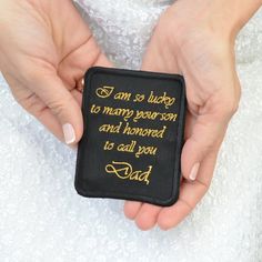 a person holding a small black and gold embroidered brooch with the words i am so lucky to marry your son and honored to call you dad