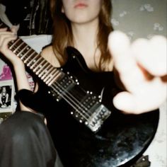 a woman holding a black electric guitar in her hand