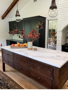 the kitchen island is made out of wood and has white marble counter tops, with two hanging lights above it