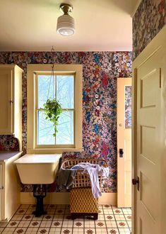 a bath room with a tub a sink and a window next to a wallpapered wall