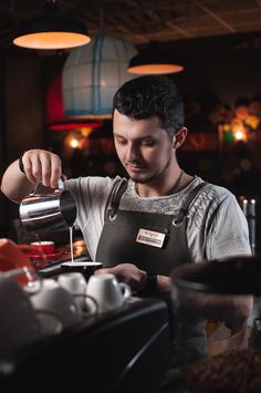 a man in an apron pours coffee into a cup