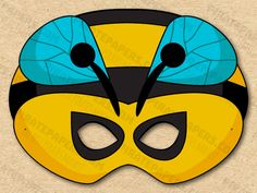 a yellow and black mask with two blue wings on the top, one is wearing a bee