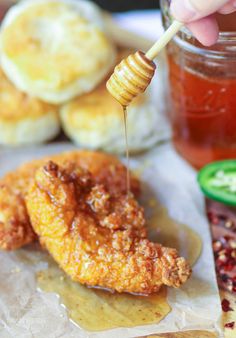 a person holding a honey stick over some food