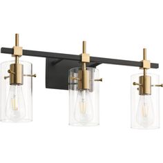 three light bathroom fixture with clear glass shades and brass accents on an aged black finish