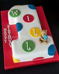 a birthday cake for a one year old with the letter j on it and a teddy bear