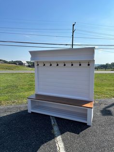 a white bench sitting in the middle of a parking lot next to a green field