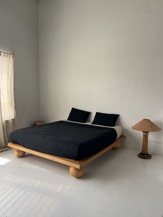 a bed sitting in the middle of a room next to a lamp and window with curtains