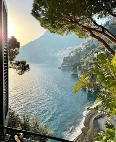 the sun is setting over the water and mountains in the distance, as seen from a balcony