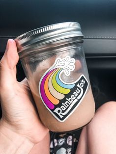 a person holding up a cup with a rainbow sticker on the side of it