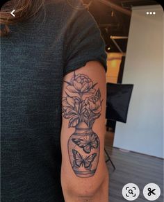 a woman with a tattoo on her arm holding a vase filled with flowers and butterflies