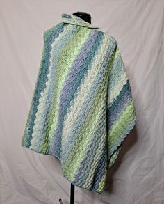 Crochet poncho in green tones for women. A light weight poncho for cool days and evenings 100% acrylic handmade accessory. Made in USA. Beautiful green toned, hand crocheted poncho for any occasion.  Mid-weight yarn makes this poncho a perfect addition for cool evenings and easy enough for all day wear. Overall this poncho measures 27" wide by 54.75".  The first button is at 11" from center fold, remaining buttons follow at 3" intervals.  In total, the poncho weighs approximately 1lb 4oz. 100% acrylic, label color "sweet mints" Machine washable and dryable. Do not bleach. Do not iron. Green One Size Winter Poncho, Green One-size Winter Poncho, Green Shawl Poncho For Fall, Green Shawl Poncho One Size, One Size Green Crochet Shawl, Green One-size Shawl Poncho, Cozy One-size Green Poncho, Green Oversized Poncho, Green Beach Poncho