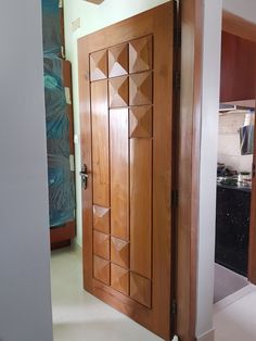 an open wooden door in a room with white flooring and wood accents on the walls