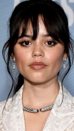 a close up of a person wearing a necklace and earrings