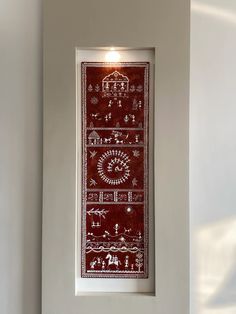 a red and white wall hanging on the side of a wall next to a window